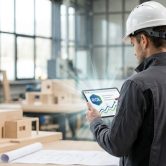 Un artisan en casque de chantier utilisant une tablette avec un graphique de croissance et le logo RGE.