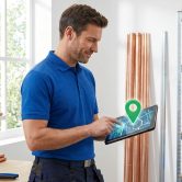 Plombier utilisant une tablette numérique avec un pointeur de géolocalisation pour gérer ses interventions.