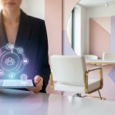 Une personne en tailleur tient une tablette avec des icônes de réseaux sociaux en hologramme dans un salon de beauté.
