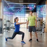 Coach sportif observant des graphiques numériques de croissance et de SEO local au-dessus d'une cliente en salle de sport.